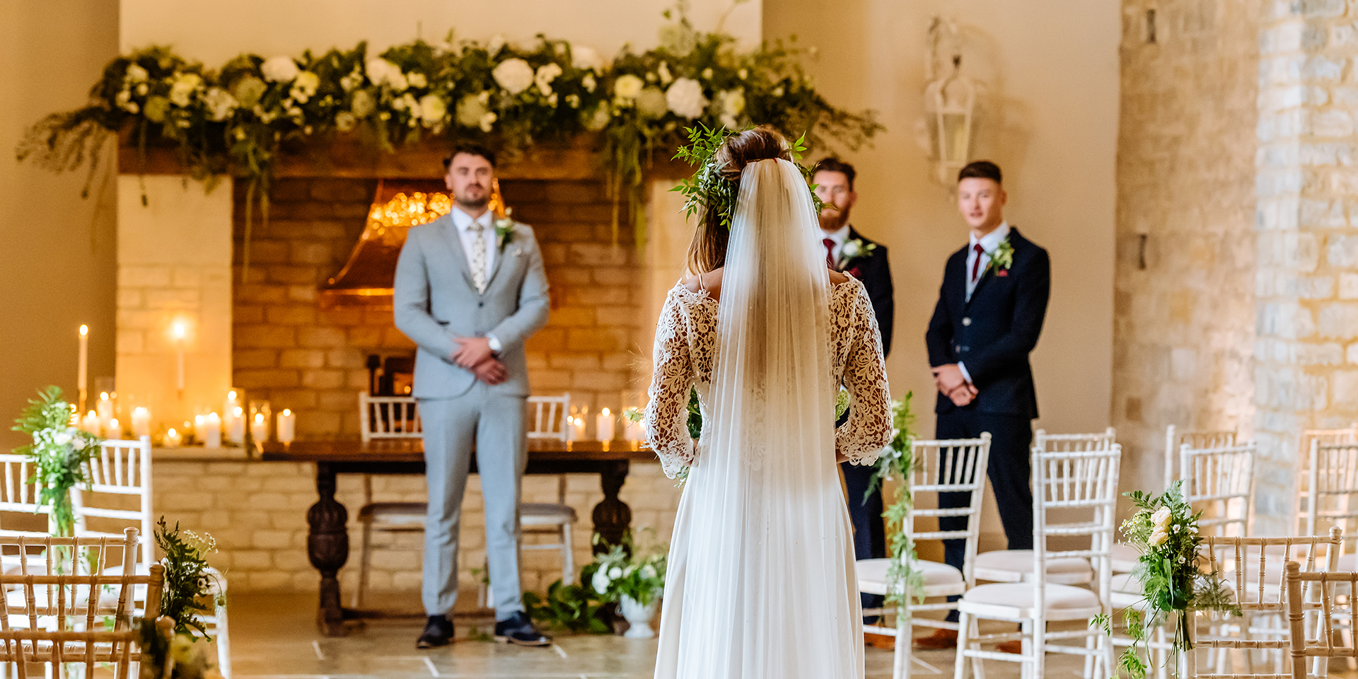 The bride walks towards her groom and the ushers in the Thatch Barn at Blackwell Grange ready for the wedding ceremony